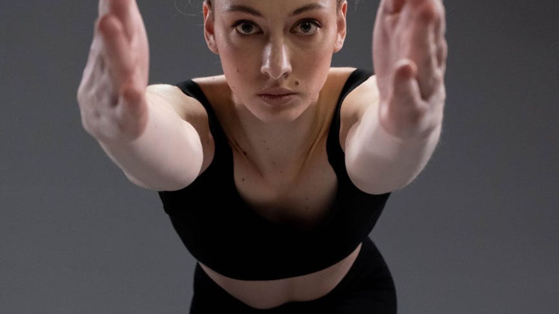Woman practicing yoga in a dark studio with neon accents